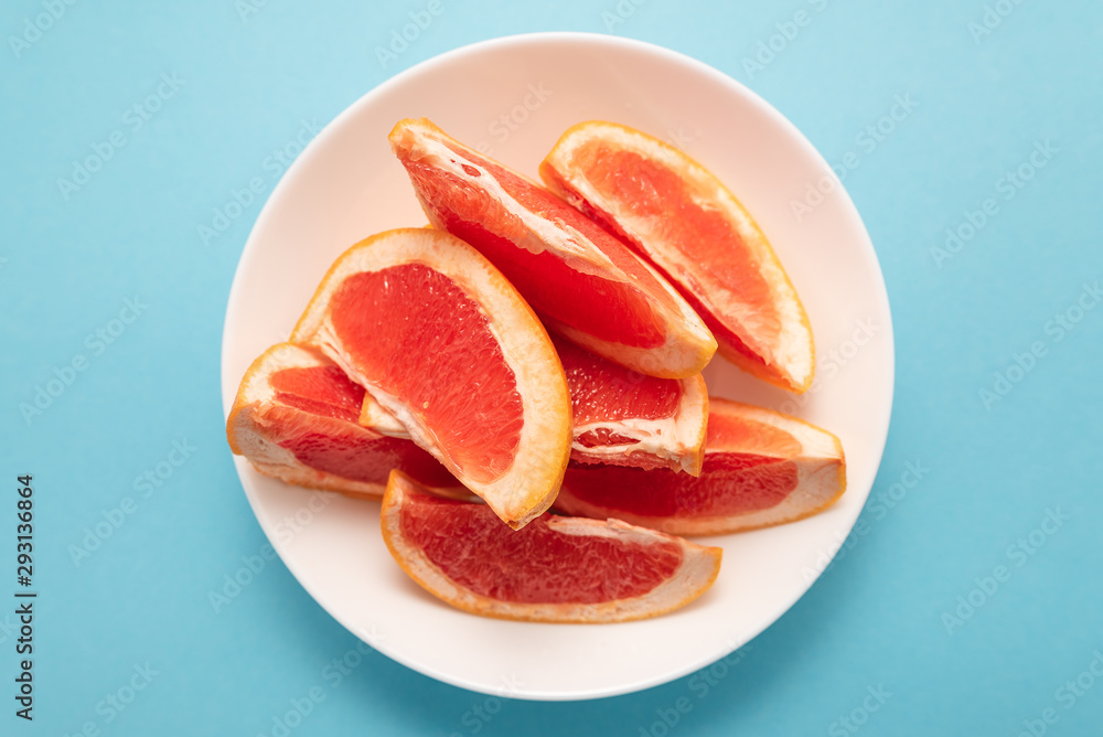 Fresh ripe juicy grapefruit on white plate on blue background. Fresh ripe juicy grapefruit on white plate on blue background.