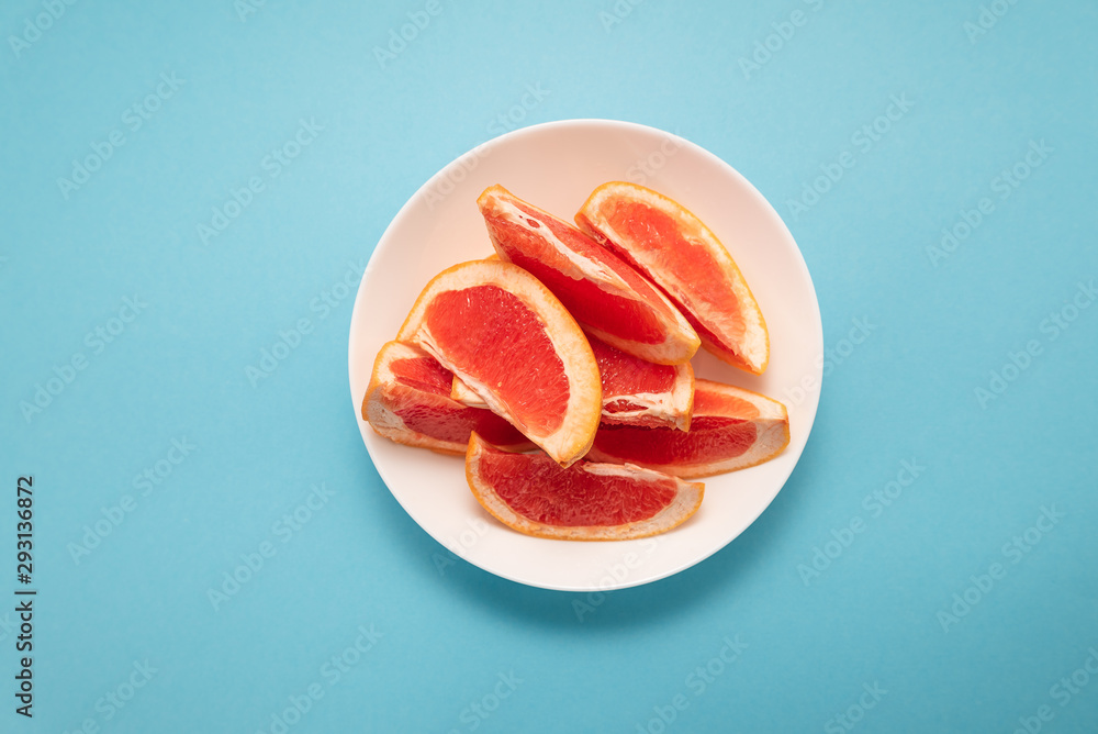 Fresh ripe juicy grapefruit on white plate on blue background. Fresh ripe juicy grapefruit on white plate on blue background.