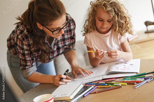 Tableau sur toile Mother helps her daughter with homework assignment .