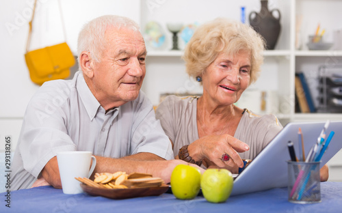 Happy elderly pair using laptop at home