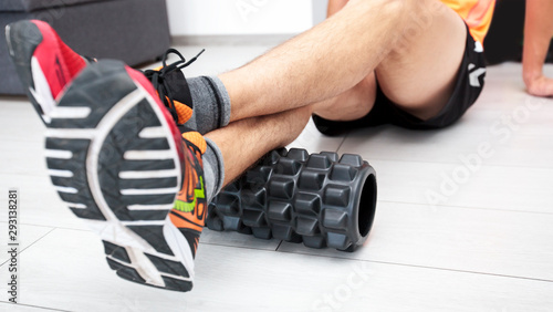 The man is massaging his muscles by the foam roller photo