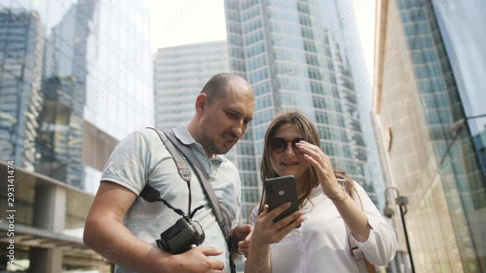 Loving couple in the downtown plan the route of your journey using the app on the smartphone. Loving couple in the downtown plan the route of your journey using the app on the smartphone.