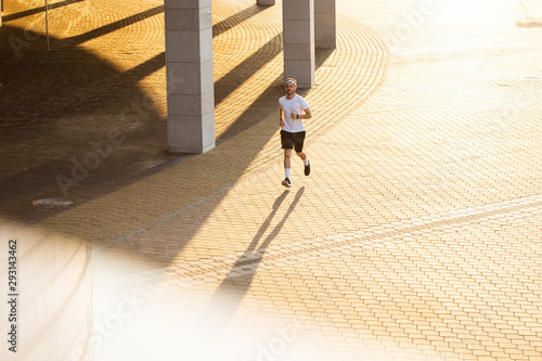 Attractive fit man running in the city at sunset. Fitness, workout, sport, lifestyle concept © opolja