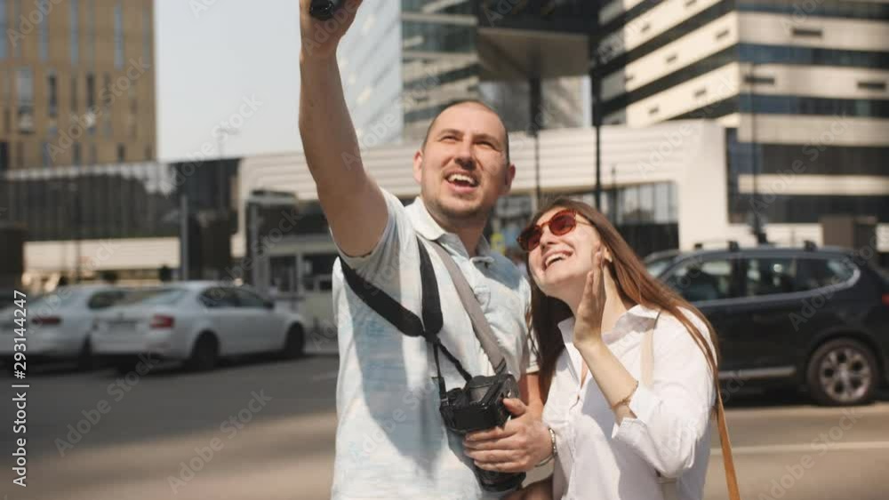 Couple of tourists bloggers shoot themselves on the background of skyscrapers in the business part of the city. Couple of tourists bloggers shoot themselves on the background of skyscrapers in the business part of the city.