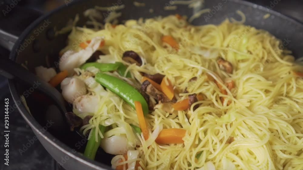Lady frying stir-Fried Vegetables With Rice Noodles on a pan. Chinese dish. Lady frying stir-Fried Vegetables With Rice Noodles on a pan. Chinese dish.