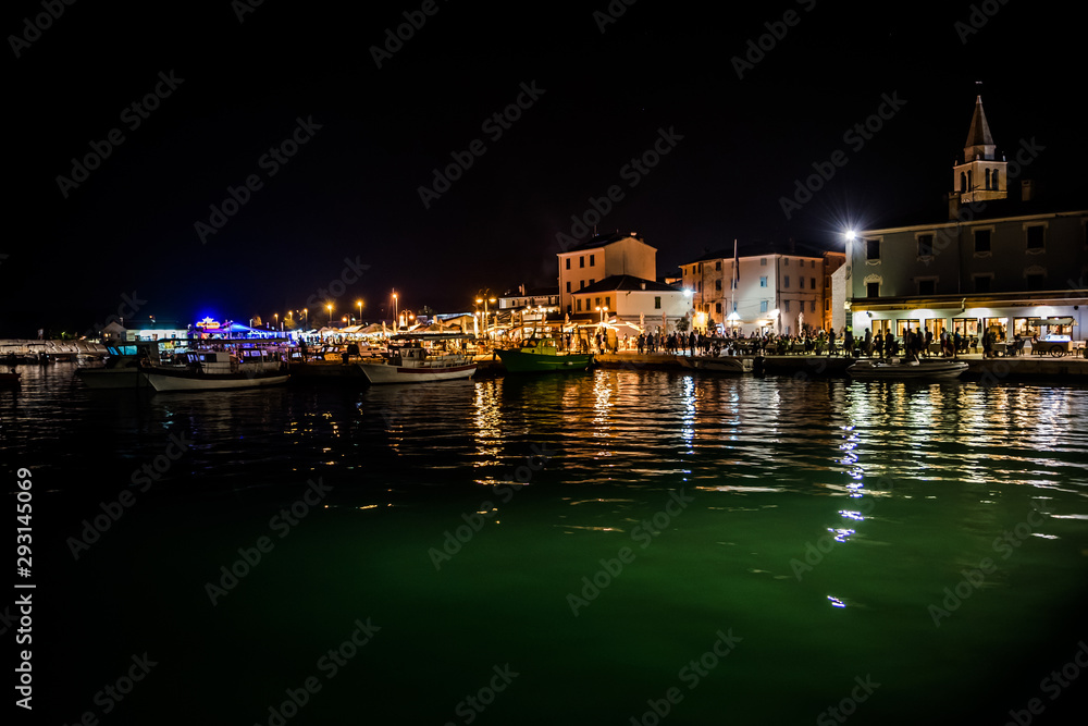 Obraz premium Illuminated Village Fazana In Croatia In The Night With Old Church And Boats In Harbor