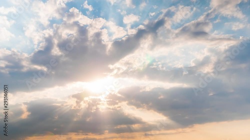 Timelapse: sun beams shining through moving dramatic white clouds. Cloudy blue sky, warm sunrise or sunset illumination, sun lens flare. Time lapse, peaceful, hope, religion, spiritual, nature concept