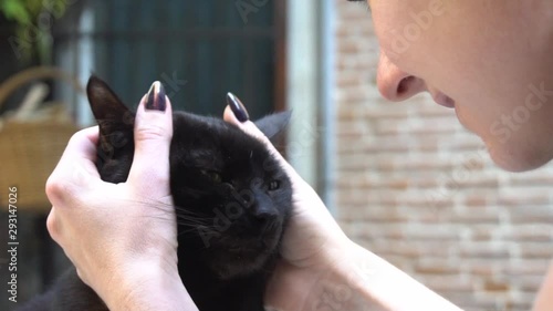 Girl playing with a black cat on the street