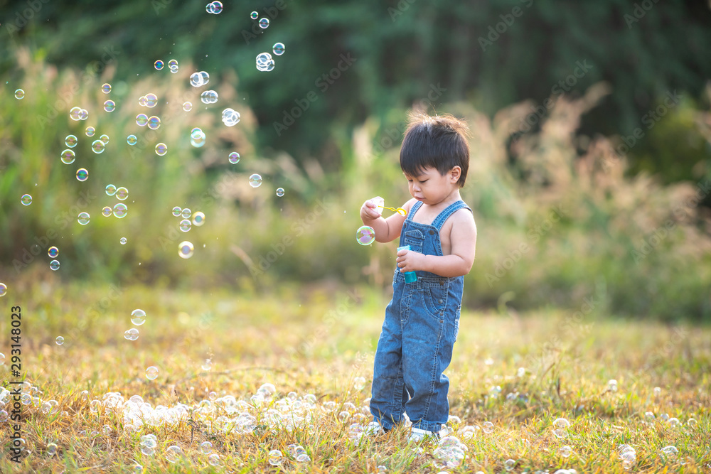 Little boy blowing soap bubbles outdoor at sunset - happy carefree childhood Little boy blowing soap bubbles outdoor at sunset - happy carefree childhood