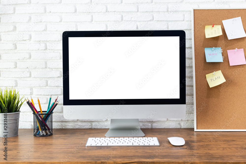 computer with blank white screen, with workspace and office supplies on a wooden desk computer with blank white screen, with workspace and office supplies on a wooden desk