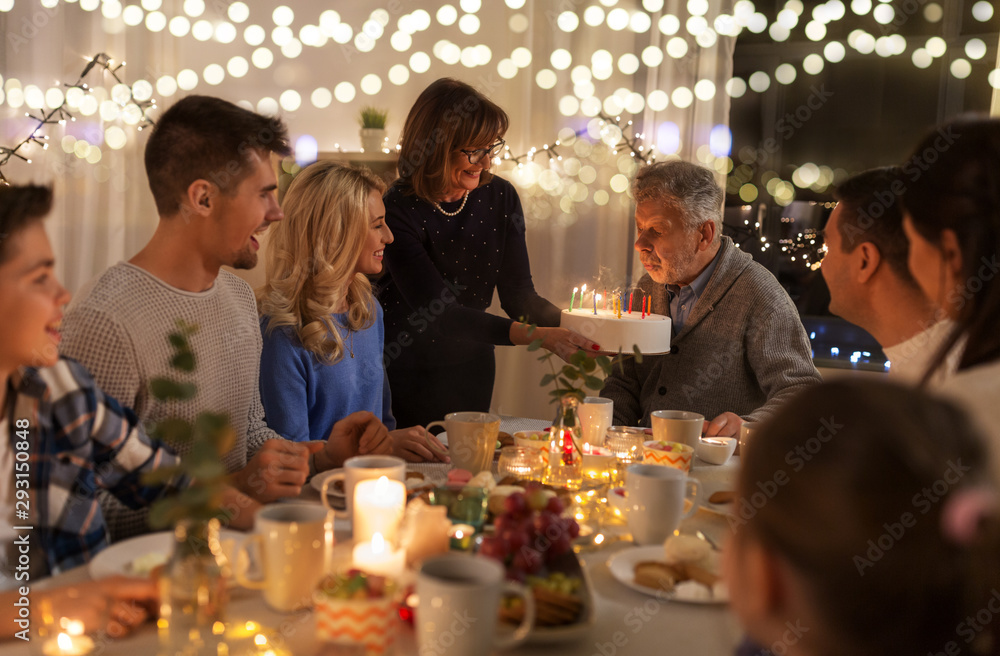 celebration and family concept - happy grandfather blowing candles on birthday cake at dinner party at home celebration and family concept - happy grandfather blowing candles on birthday cake at dinner party at home