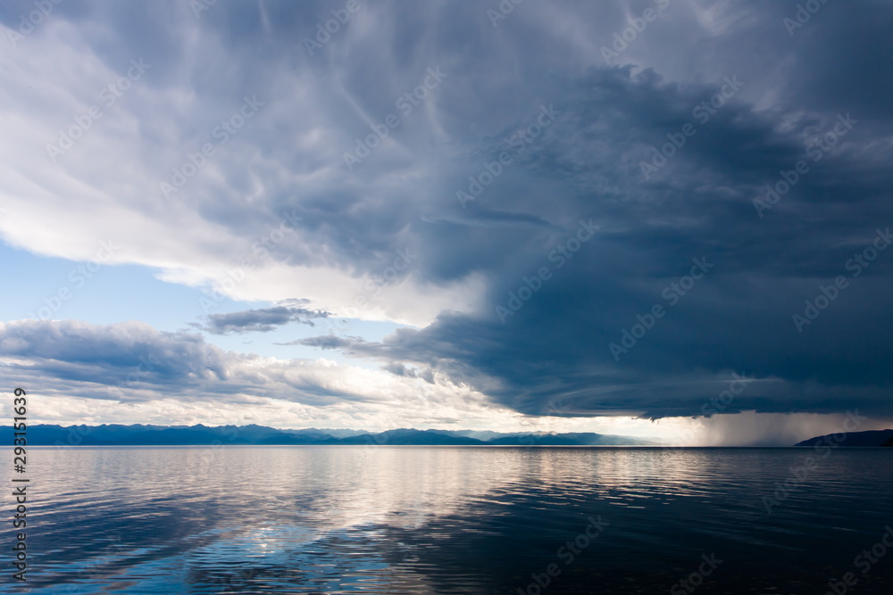 Obraz premium Storm with heavy rain and bright sun over the shore of lake Baikal