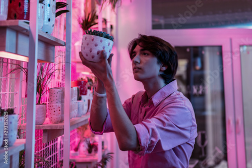 Foto Good looking interested man looking closely at plant in a pot