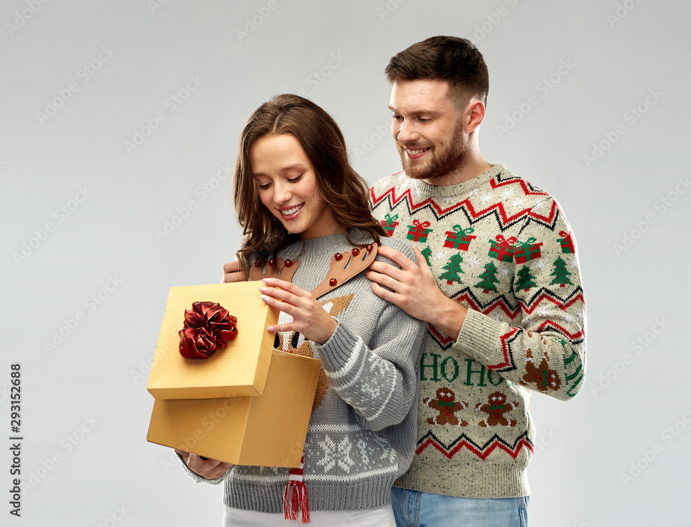 people and holidays concept - portrait of happy couple with christmas gift at ugly sweater party people and holidays concept - portrait of happy couple with christmas gift at ugly sweater party