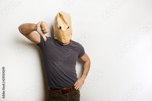 Uomo con busta di carta in testa va il dito riv verso il basso su sfondo bianco photo