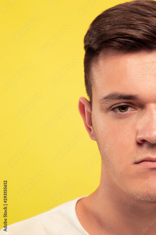 Fototapeta premium Caucasian young man's close up portrait on yellow studio background. Beautiful male model with well-kept skin. Concept of human emotions, facial expression, sales, ad. Looks sad and upset.