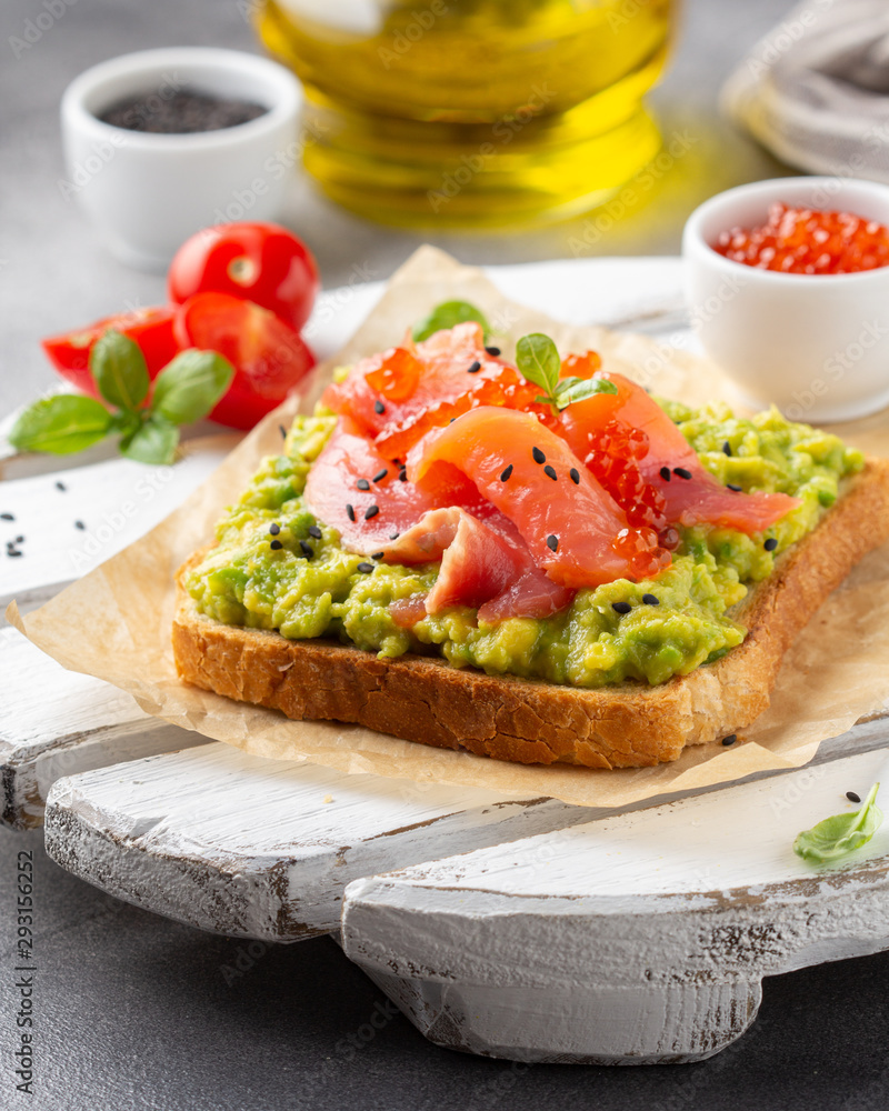 Toast with avocado, red fish (salmon, trout), caviar and black sesame. Tasty, bright, delicious healthy breakfast or lunch Toast with avocado, red fish (salmon, trout), caviar and black sesame. Tasty, bright, delicious healthy breakfast or lunch