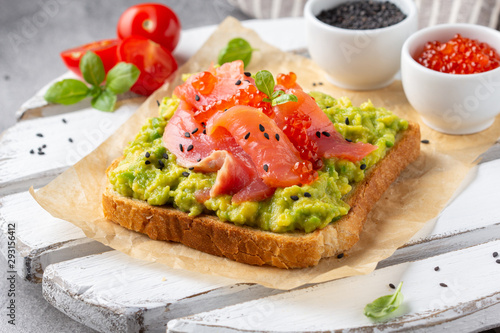 Toast with avocado, red fish (salmon, trout), caviar and black sesame. Tasty, bright, delicious healthy breakfast or lunch