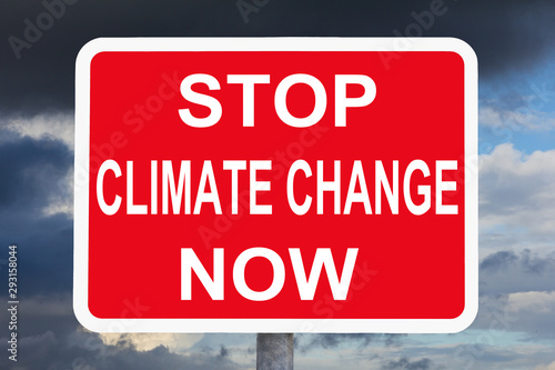 Climate change concept: STOP CLIMATE CHANGE NOW text on red and white warning sign in front of dark sky.