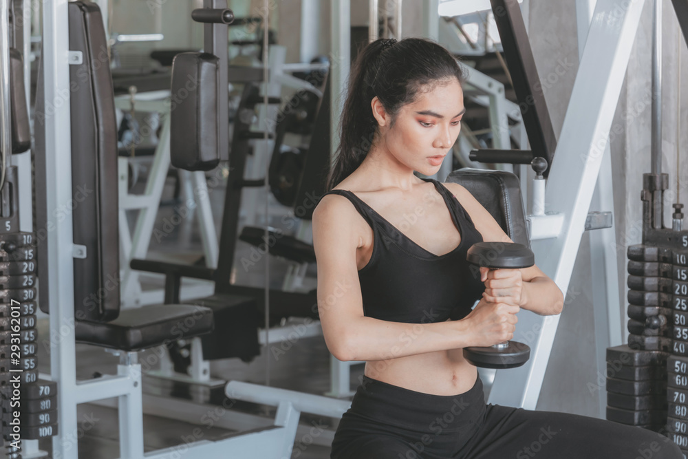 Beautiful women fit serious work out in gym alone with dumbbells. Healthy and Exercise lifestyle Beautiful women fit serious work out in gym alone with dumbbells. Healthy and Exercise lifestyle