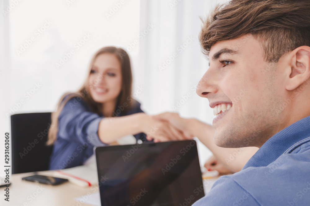 Obraz premium Happy smiling handsome caucasian businessman and businesswoman casual wear shaking hands sitting on desk in modern office, Welcome to team Meeting, negotiation, greeting business Partnership