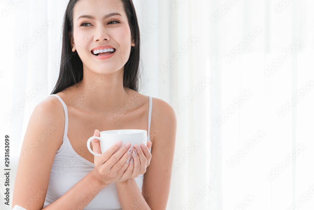 Healthy young beautiful woman smile happy use two hand to hold a cup of coffee on bedroom in morning Healthy young beautiful woman smile happy use two hand to hold a cup of coffee on bedroom in morning