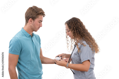 Caucasian young nurse girl with glasses taking blood pressure to a patient with a tensiometer in background isolated photo