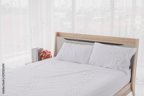 White bedroom interior with windows. Clean white bed and pillows in room.