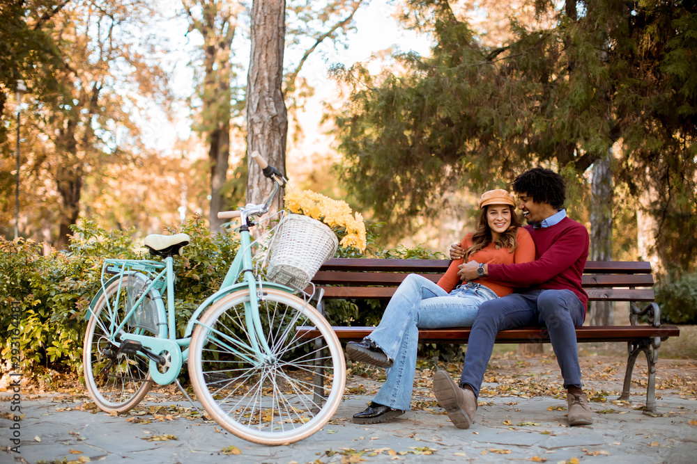 Multiratial loving couple sitting on bench in the autumn city park Multiratial loving couple sitting on bench in the autumn city park
