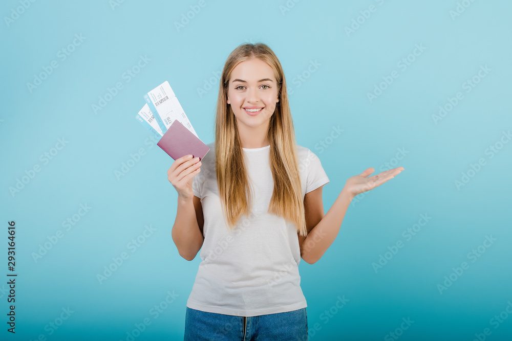 beautiful young smiling blonde girl with passport and airplane tickets isolated over blue beautiful young smiling blonde girl with passport and airplane tickets isolated over blue