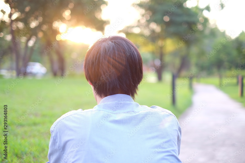 Fototapeta premium Back of alone man sit on the way in the park, background sunset.
