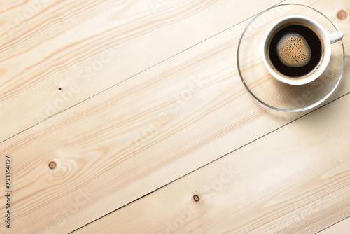 White cup of coffee on a wooden table. View from above