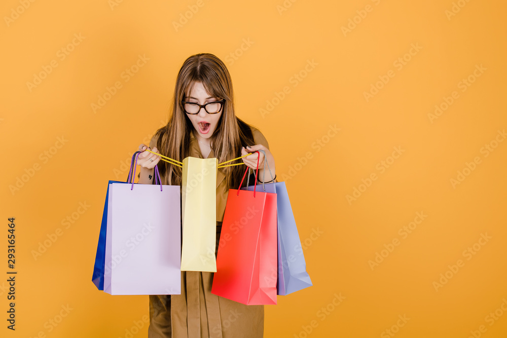 excited hipster woman with colorful shopping bags isolated over yellow