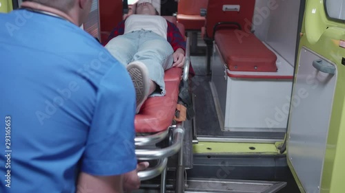 Sick woman lie on the strecher in ambulance car.