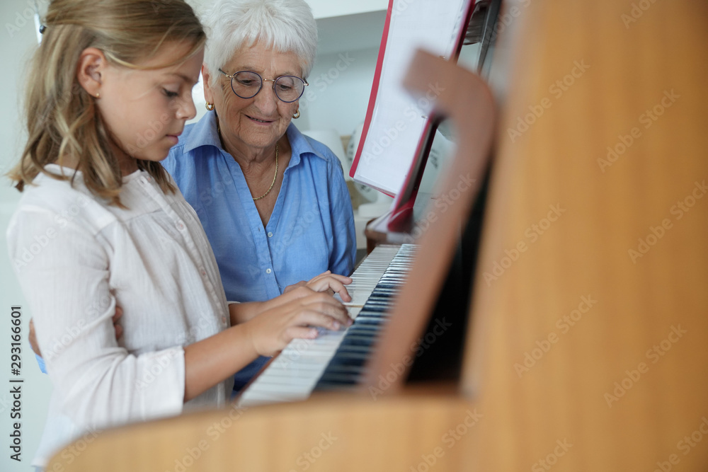 Fototapeta Mała dziewczynka gra na pianinie, babcia ją obserwuje
