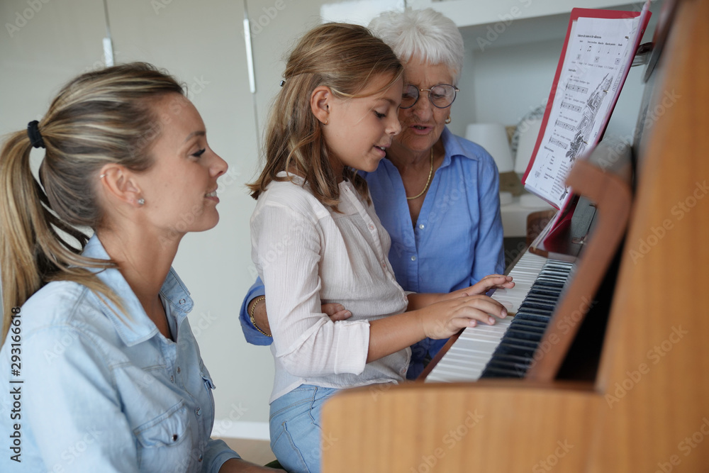 Fototapeta Mała dziewczynka gra na pianinie, mama i babcia ją obserwują