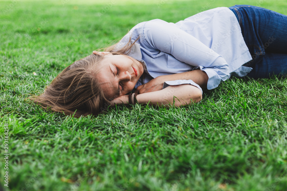 Young woman sleeping on green grass in the park Young woman sleeping on green grass in the park