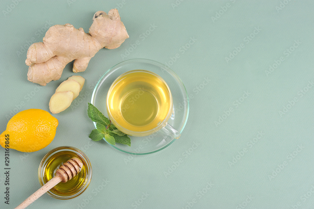 Drink with ginger and honey on a light surface. Next to the cup are the ingredients for making the drink: ginger, mint, honey and lemon. Free space for text. View from above. Drink with ginger and honey on a light surface. Next to the cup are the ingredients for making the drink: ginger, mint, honey and lemon. Free space for text. View from above.