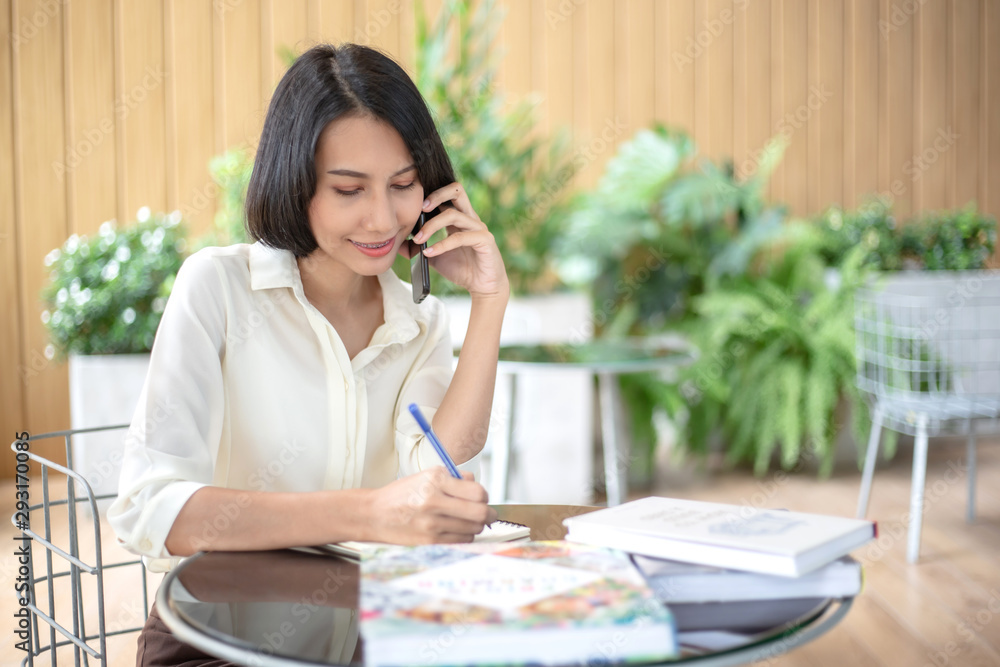 Young beautiful Asian woman reading a book while doing her homework in the modern co working space Young beautiful Asian woman reading a book while doing her homework in the modern co working space