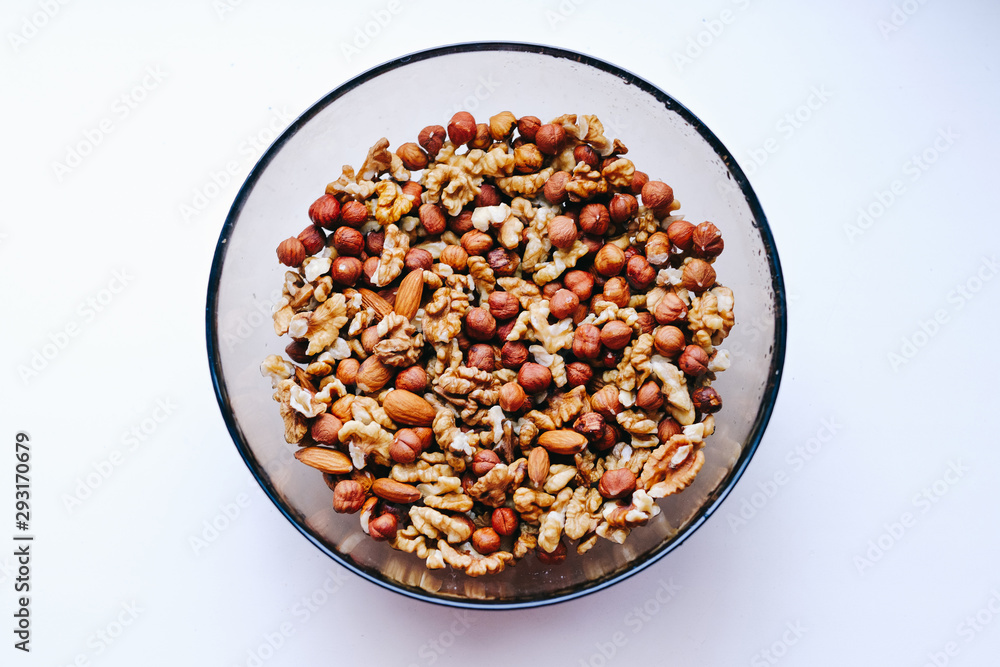 Glass plate with nuts on a white background, top view. Glass plate with nuts on a white background, top view.