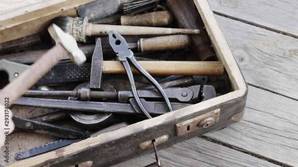 A suitcase with old hand tools closes on a wooden background A suitcase with old hand tools closes on a wooden background