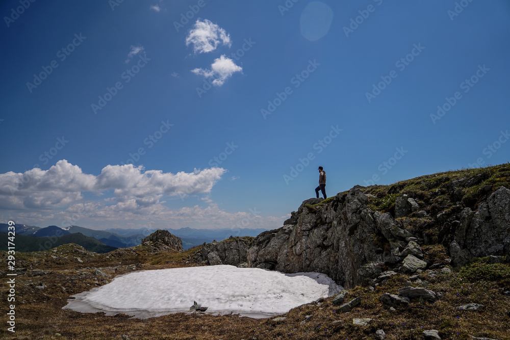 A man standing on rocks in front of sky background A man standing on rocks in front of sky background