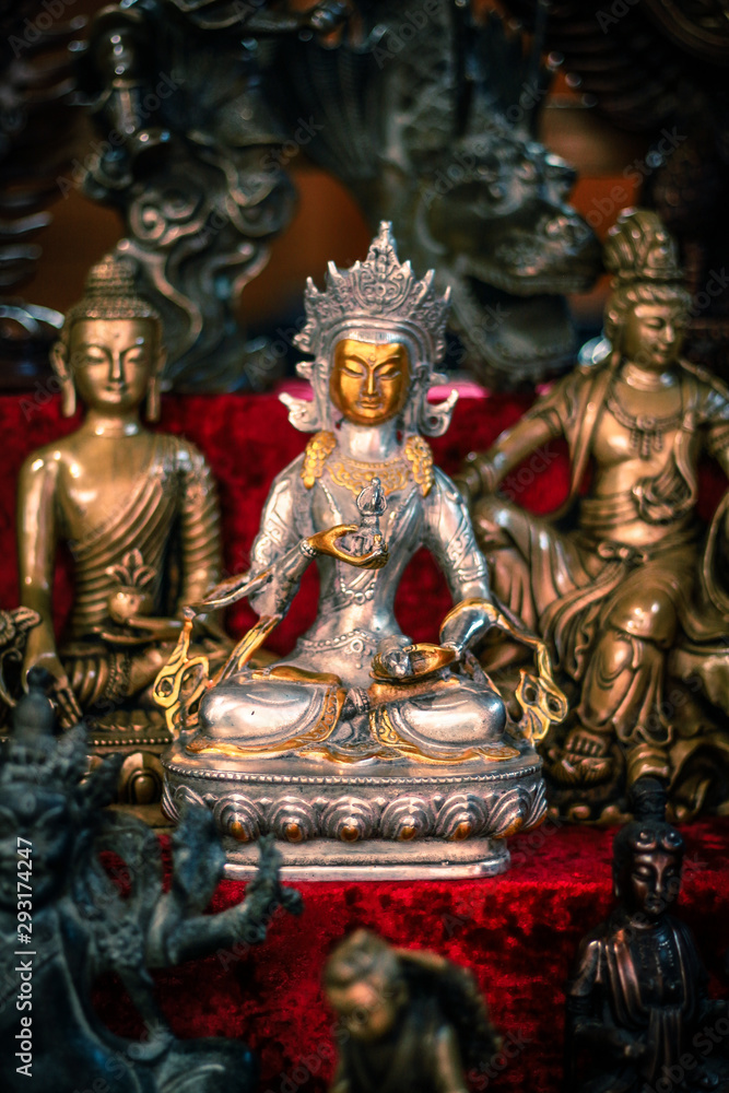 Buddhist figurines and masks of mythological characters in gold and bronze on a burgundy with a red background