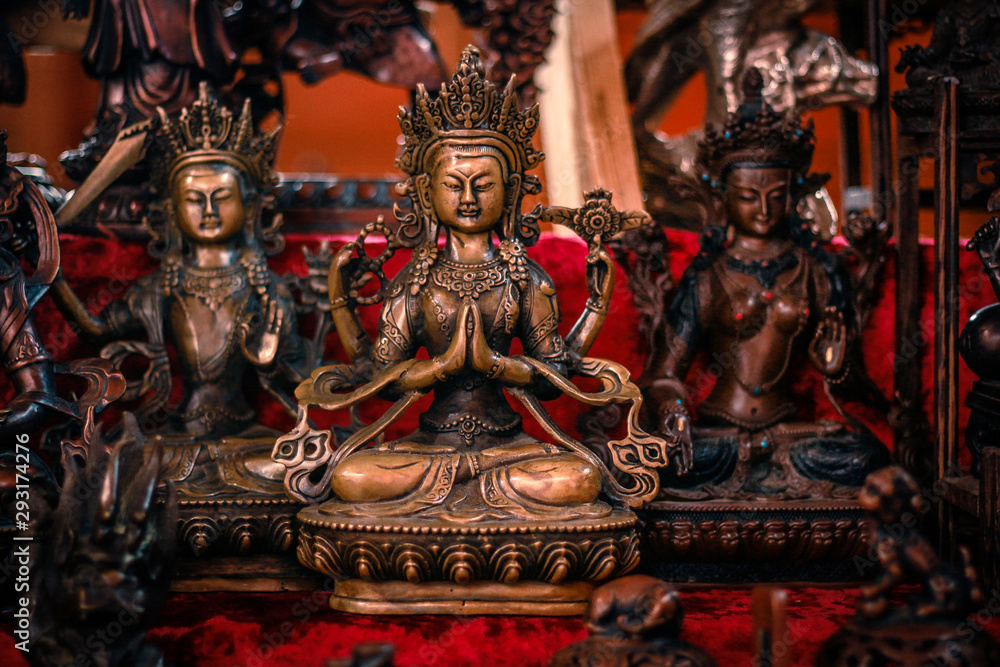 Buddhist figurines and masks of mythological characters in gold and bronze on a burgundy with a red background