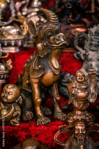 Buddhist figurines and masks of mythological characters in gold and bronze on a burgundy with a red background