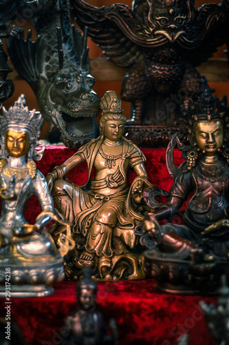 old market counter Buddhist figurines and masks of mythological characters in gold and bronze on a burgundy with a red background
