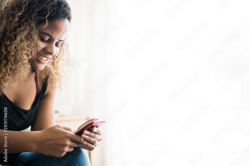 Girl watching a social media live stream.African woman with beautiful smile hold mobile phone during rest in coffee shop near window. Girl watching a social media live stream.African woman with beautiful smile hold mobile phone during rest in coffee shop near window.