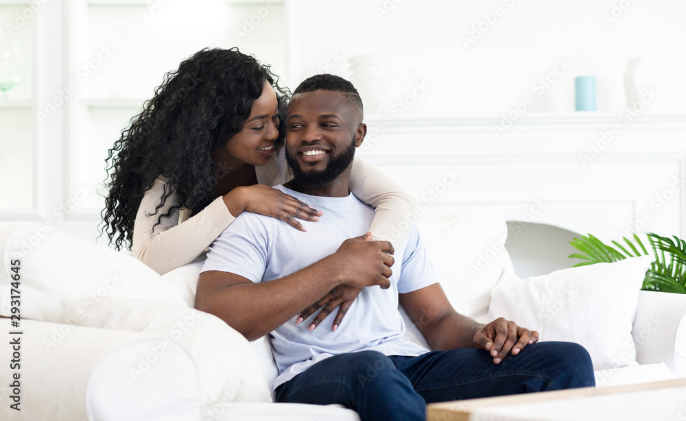 Obraz premium Playful african american woman whispering something to her boyfriend's ear