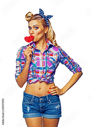 Surprised woman eating heart shape lollipop. Girl in pin up cloth. Blond model at retro fashion and vintage concept. Isolated over white background. Raster illustration. photo