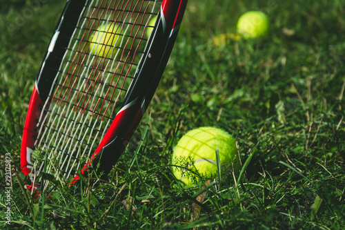 Tennis balls with a racket lying on the grass